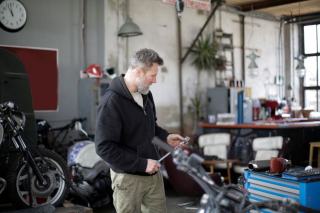 Mécanicien préparant ses outils dans un atelier entouré de motos