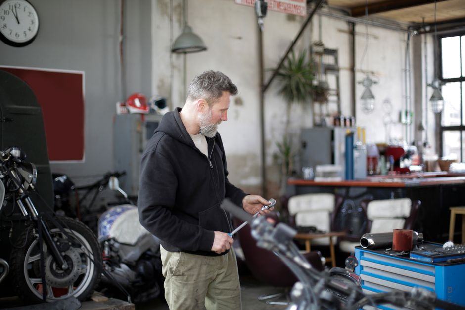 Mécanicien préparant ses outils dans un atelier entouré de motos