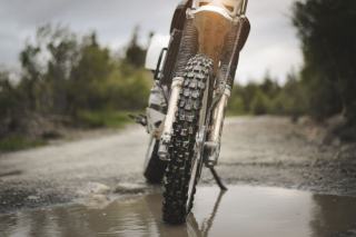 Pneu avant à crampons d’une moto tout-terrain sur un chemin mouillé