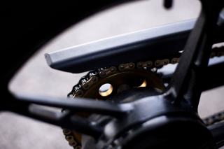 Chaîne dorée et couronne arrière d’une moto sous le garde-chaîne